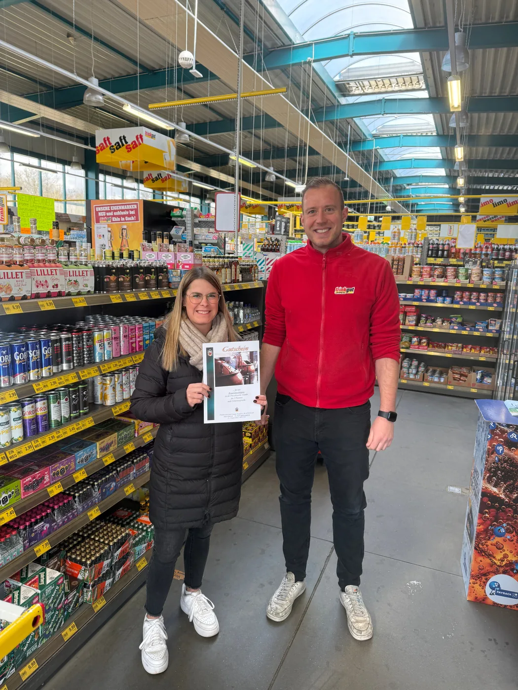 Twee personen bij een prijsuitreiking met een oorkonde in de winkel